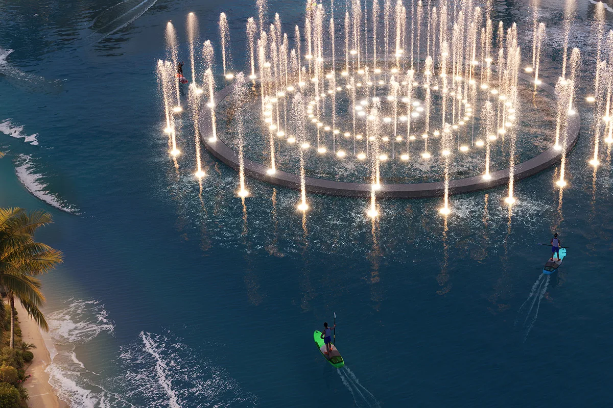 Illuminated fountain ring in the central lagoon at dusk, with paddle-boarders and a palm-lined shore, DAMAC Islands