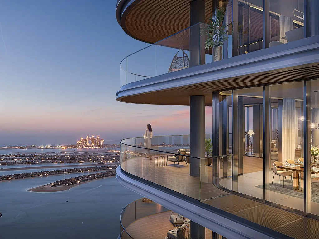 Curved glass balcony at dusk with Palm Jumeirah views and a lit dining room, Bayview