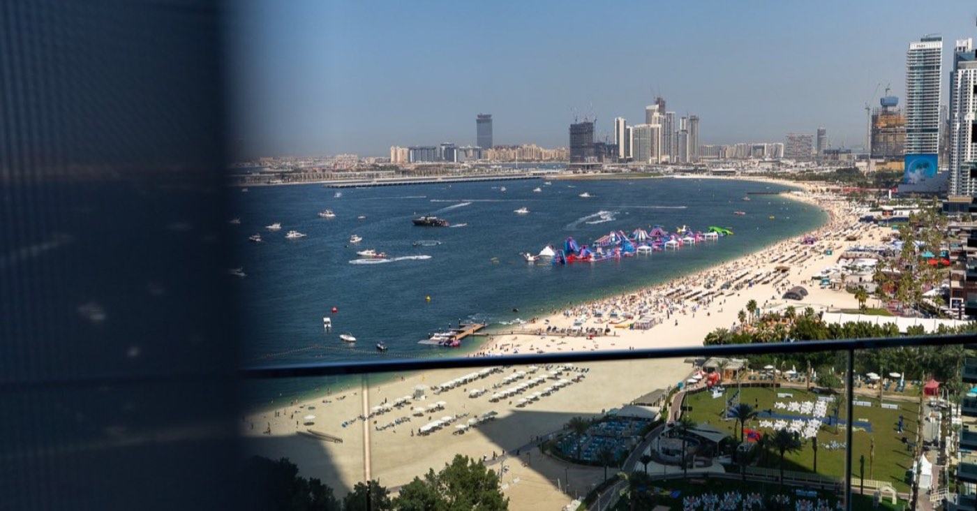 The Jumeirah Beach Residence shoreline in Dubai photographed from a JBR tower balcony, showing the beach, sun loungers and the Gulf - the coastline on which Sensoria at FIVE LUXE sits