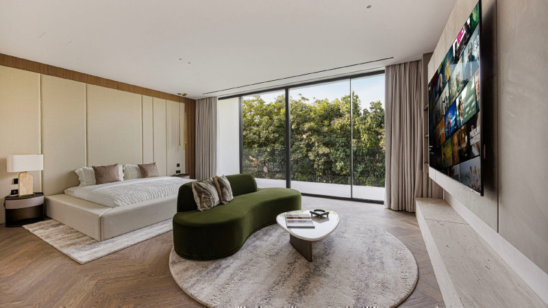 Principal bedroom with floor to ceiling glass looking into a green tree canopy in an Al Barari villa Dubai