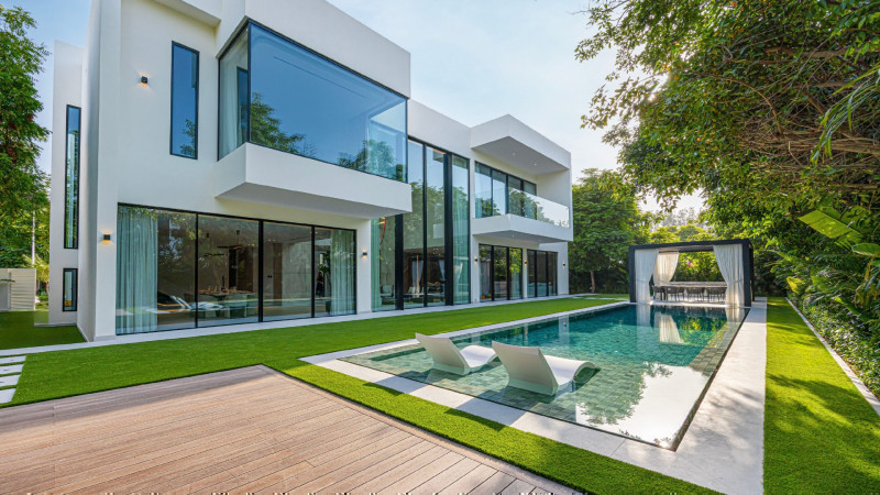 Contemporary white villa with swimming pool surrounded by mature green trees in Al Barari Dubai